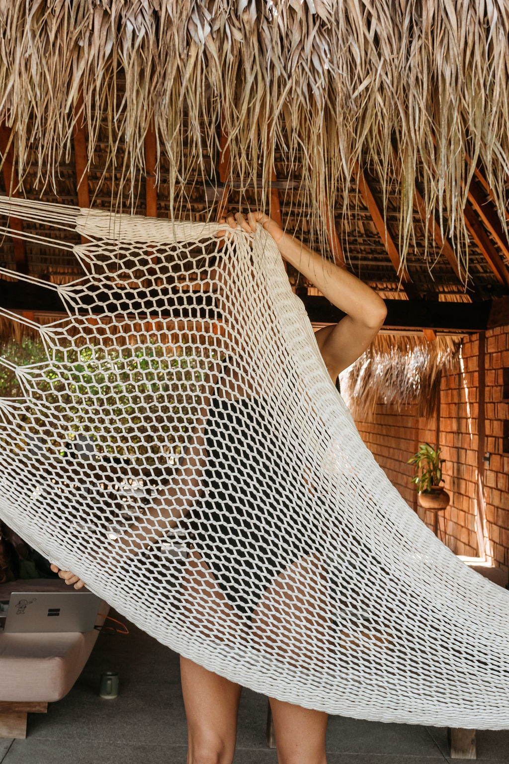 Person in a swimsuit behind a woven hammock under a thatched palapa roof at Casa Libra in Mexico