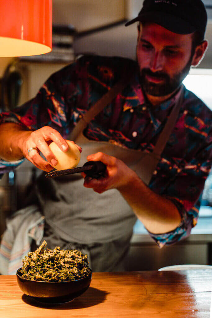 Chef preparing food with a grater in a kitchen