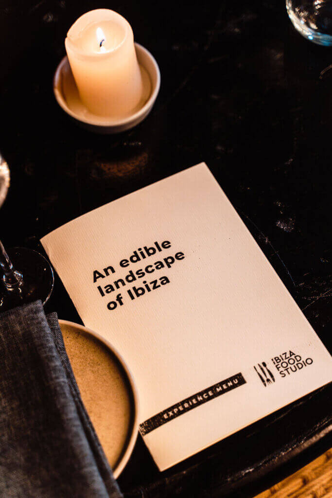 Ibiza Food Studio experience menu on a dining table with a lit candle