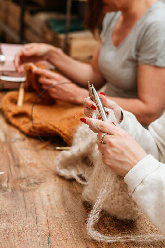 Woman knitting with wool yarn on a wooden table