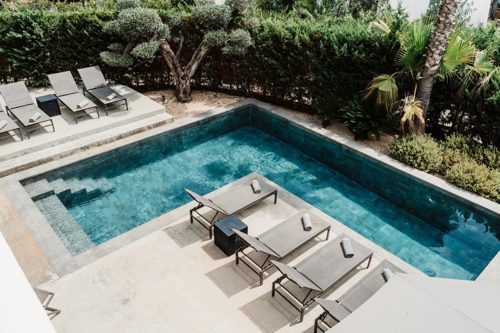 Swimming pool and sun loungers at Sa Brisa Villa in Santa Eulalia, Ibiza, viewed from above.