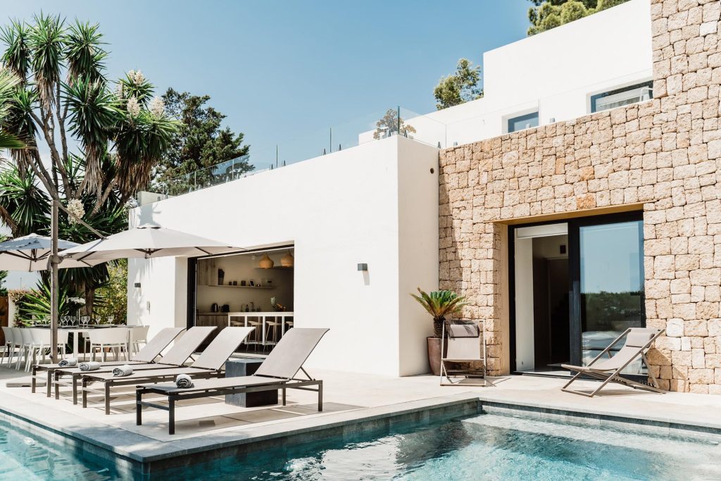 Sa Brisa Villa in Santa Eulalia, Ibiza, with a stone-clad facade, pool, and sun loungers.