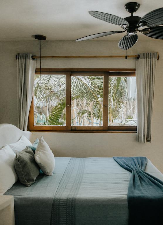 Bed with pillows and colorful cushions beside a window