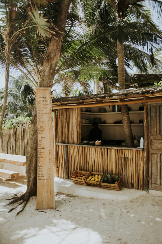 Rustic thatched taco shack with a handwritten menu and baskets of produce.