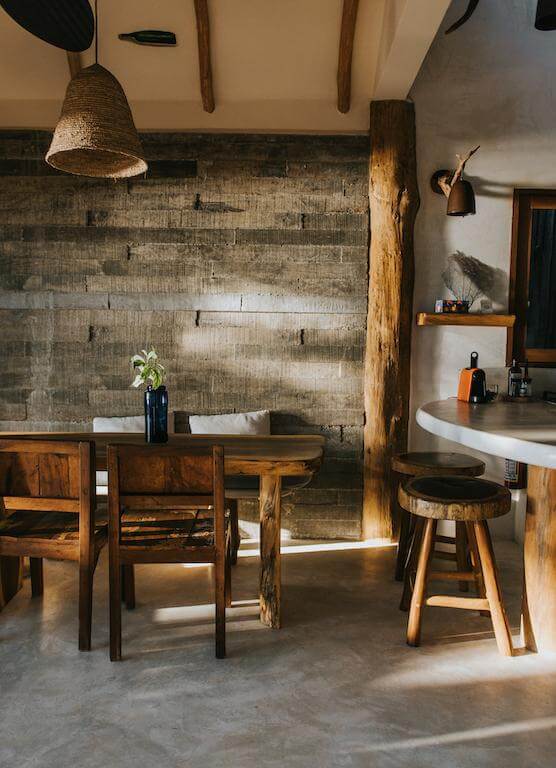 Wooden dining table and chairs beside a textured wood wall and kitchen counter.