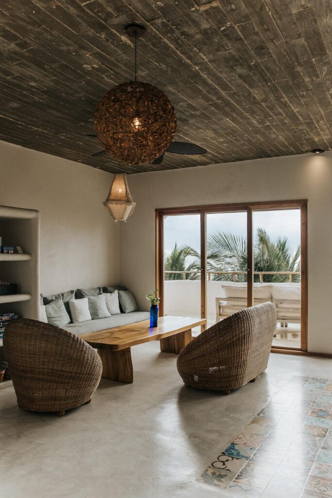 Living room with wicker chairs, a built-in sofa, and a wooden coffee table beside balcony doors.