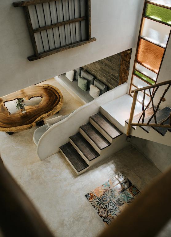 Overhead view of the staircase descending beside a curved sofa and live-edge wood table.