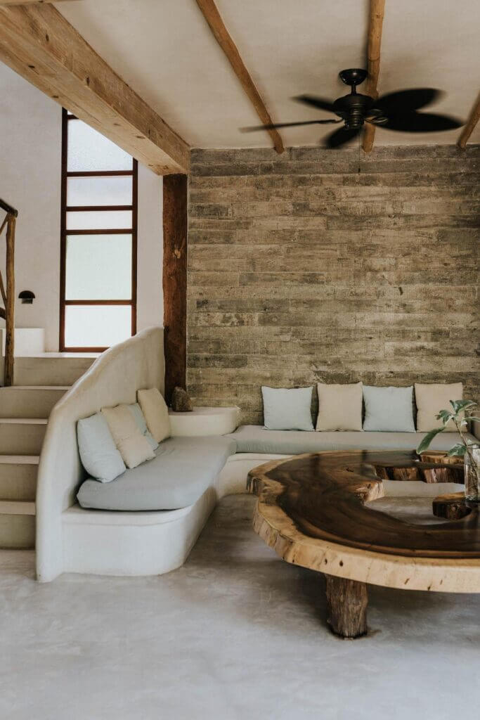 Built-in curved sofa and sculptural wood coffee table beside a wood-paneled wall.
