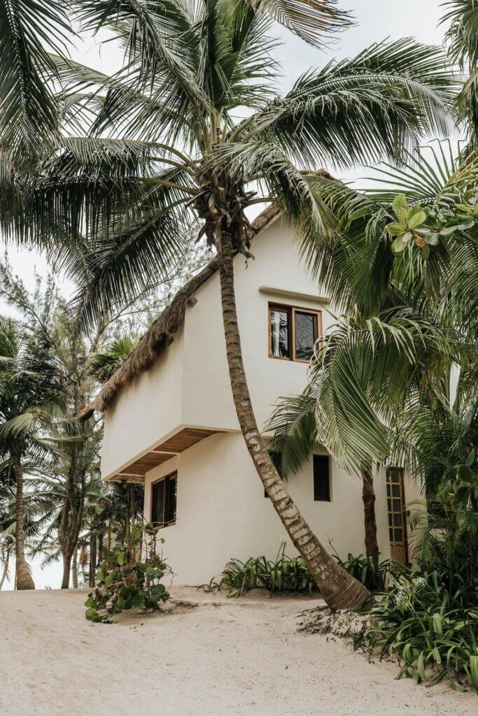 White villa framed by tall palms in a sandy courtyard.