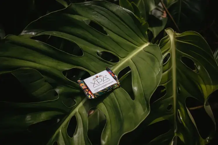 A close-up shot of a small, artisanal bar of soap in a colorful, patterned wrapper labeled 