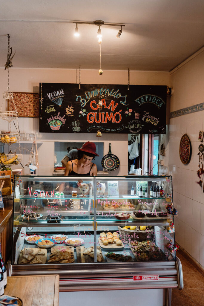 Worker behind the counter at Can Guimó, a bakery displaying pastries and vegan treats.