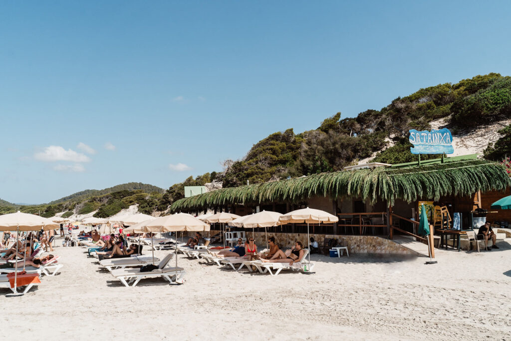 Sa Caleta Villa, Ibiza: Sa Trinxa beach club, with sun loungers and parasols on the sandy shore.