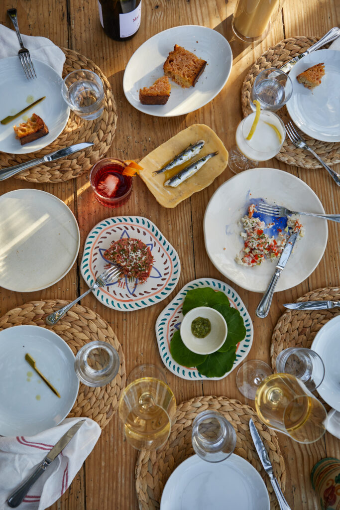 Breakfast spread with pastries, small fish, drinks, and set tableware.