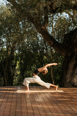 Woman practicing yoga on a wooden deck surrounded by trees