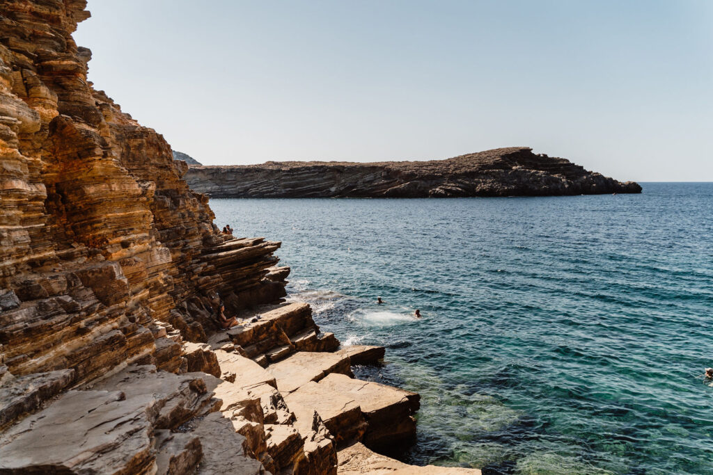 Can Beia Villa, Ibiza: swimmers in the sea beside the layered rock terraces of Punta Galera.