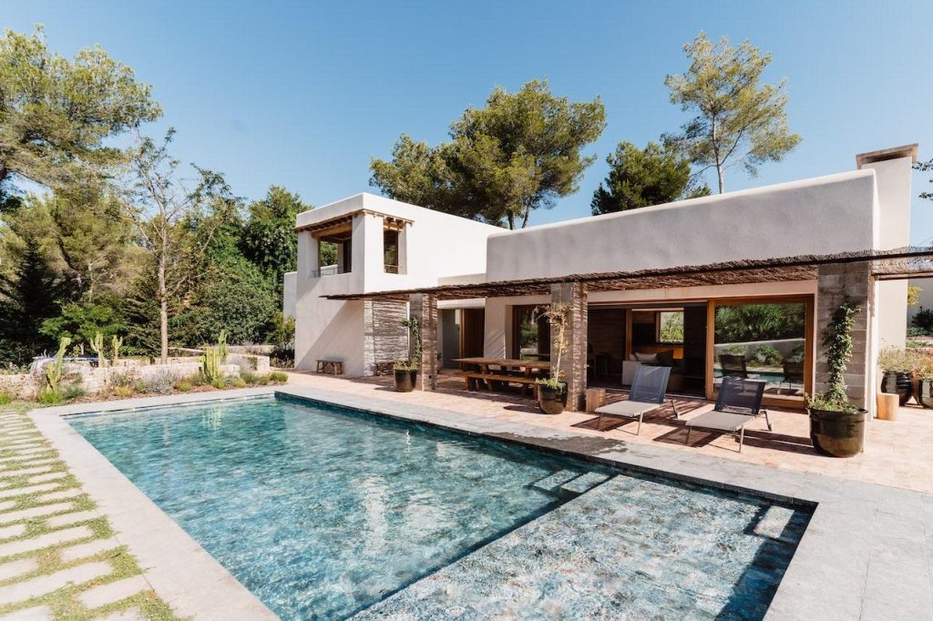 Can Beia Villa in Ibiza, with a swimming pool, sun loungers, and surrounding pine trees.