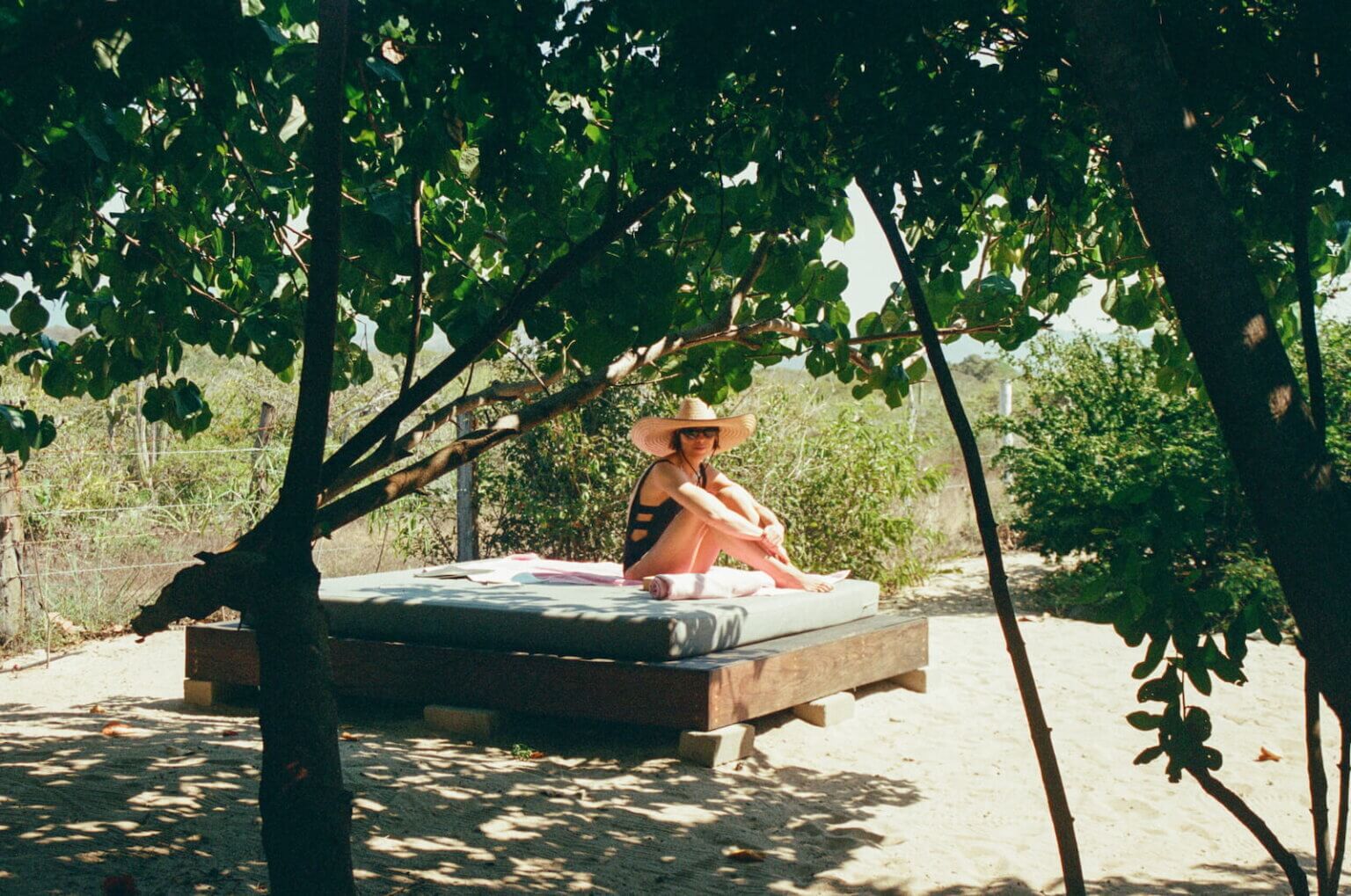 Person wearing a straw hat on a shaded outdoor daybed on the sand at Casa Libra in Mexico