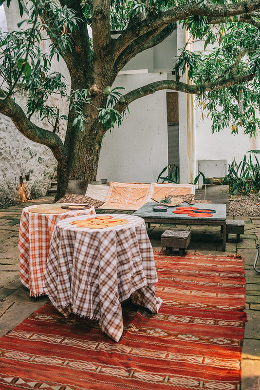 Historic courtyard with a large tree, outdoor seating, and colorful woven rugs in Honda, Colombia