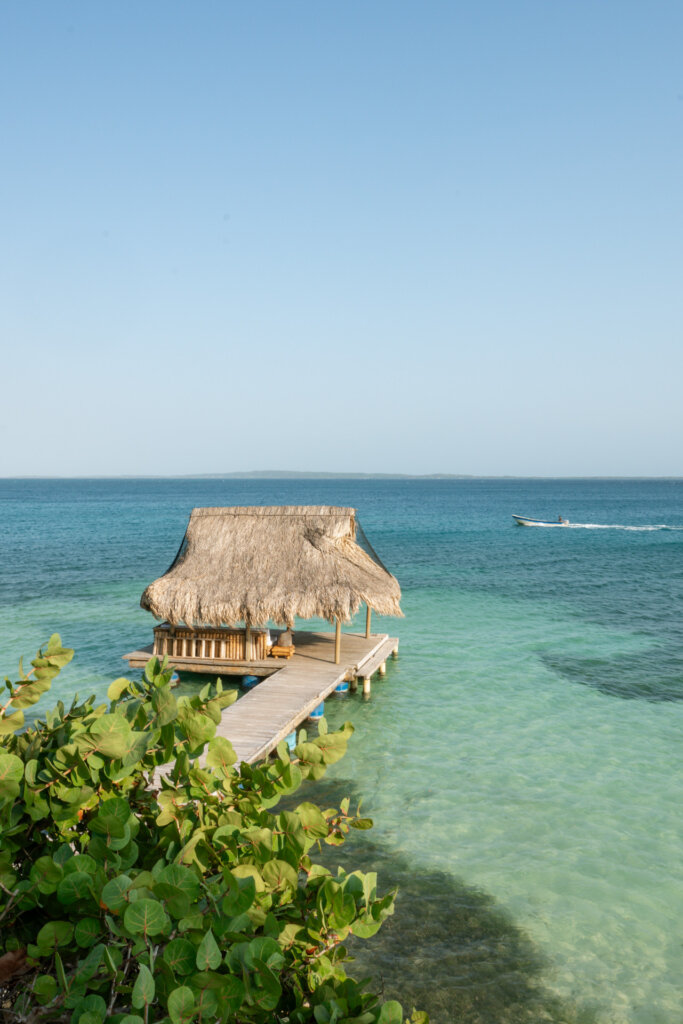 Thatched-roof pavilion and wooden dock overlooking turquoise waters in the Rosario Islands, Colombia