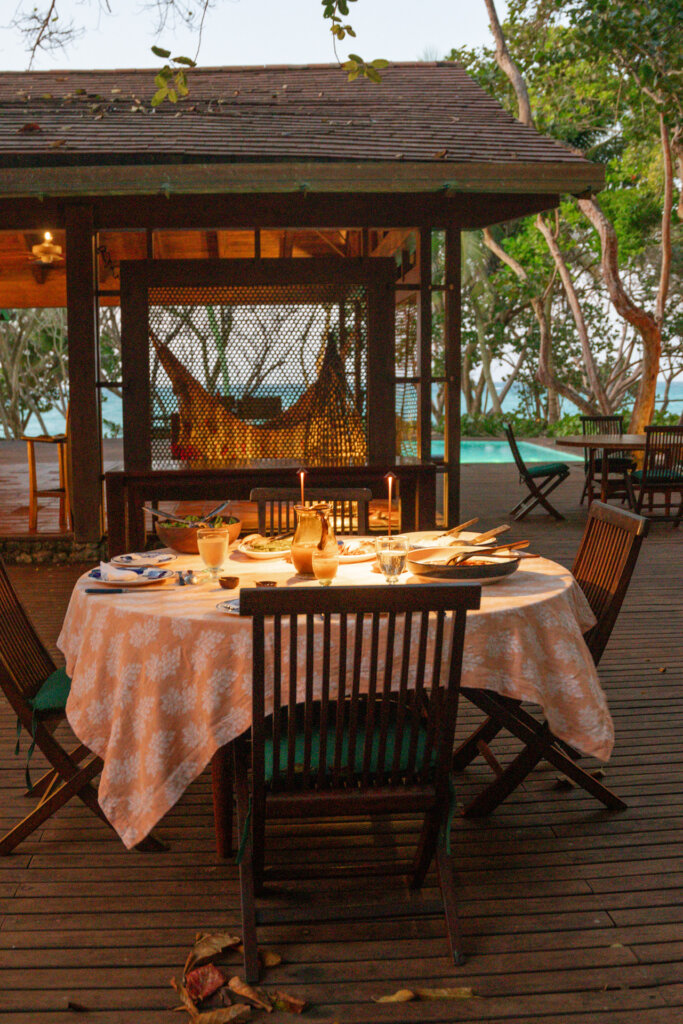 Outdoor dining area with a candlelit table, hammock, and pool at a luxury villa in the Rosario Islands, Colombia