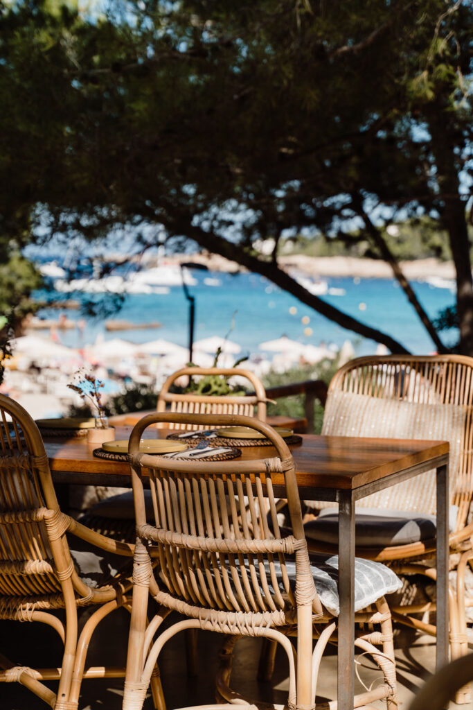 Outdoor dining table beneath a tree at Rebrots, overlooking the Ibiza coast.