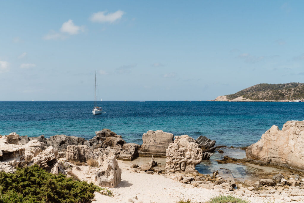 Rocky shoreline and clear blue water at Ses Salines beach, Ibiza.