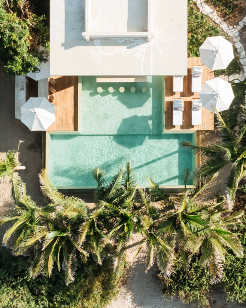 Overhead view of the pool, sun loungers, and umbrellas beside the villa.