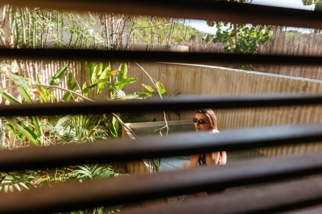 Guest in the pool seen through horizontal wooden slats.