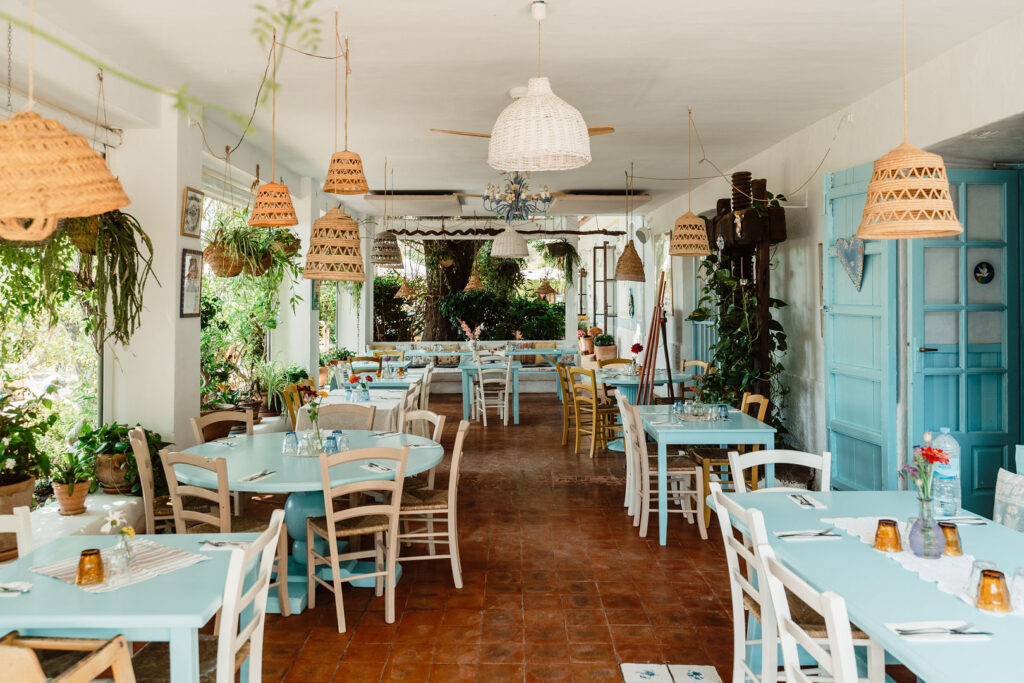 La Paloma’s bright dining room with turquoise tables, wicker pendant lights and garden views.