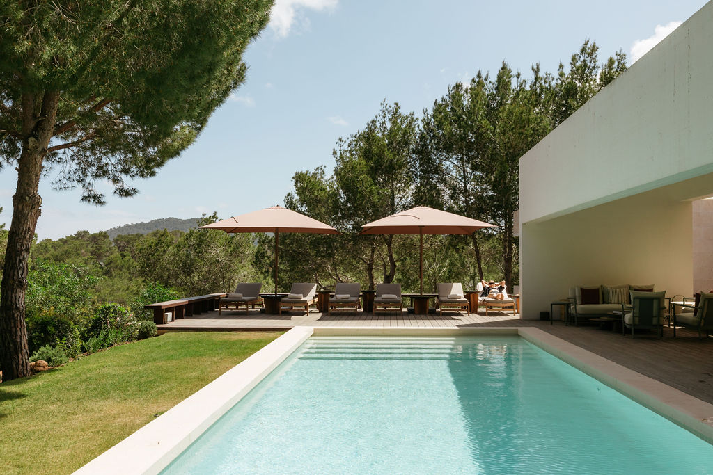Villa Arcana’s pool, sun loungers and parasols beside a modern Ibiza villa.