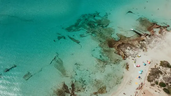 An aeriel shot of crystalline waters and parasols from above at the beach Formentera