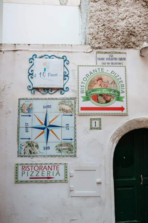 Exterior wall with colorful signs, including a compass rose, restaurant signage 