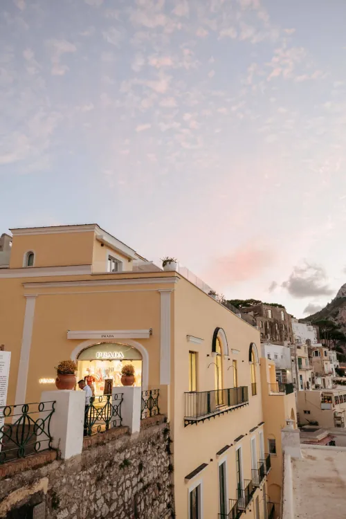 A pastel pink and blue sky over a charming yellow building with arched windows and a 