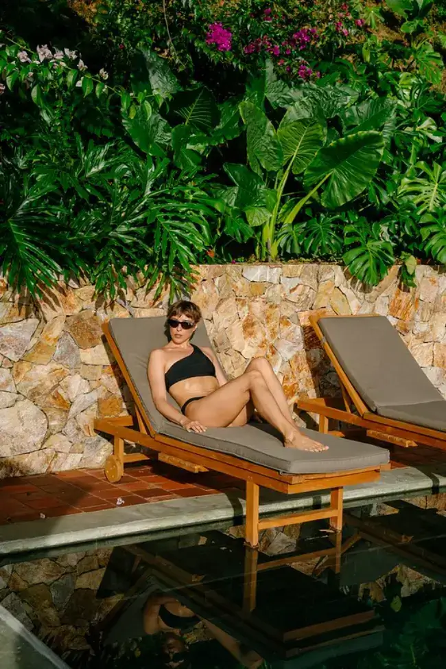Woman relaxing on a poolside lounger surrounded by tropical plants in Antioquia, Colombia