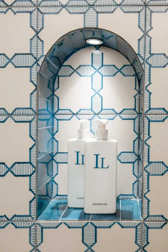 Illuminated alcove with white shampoo and shower gel bottles labeled 