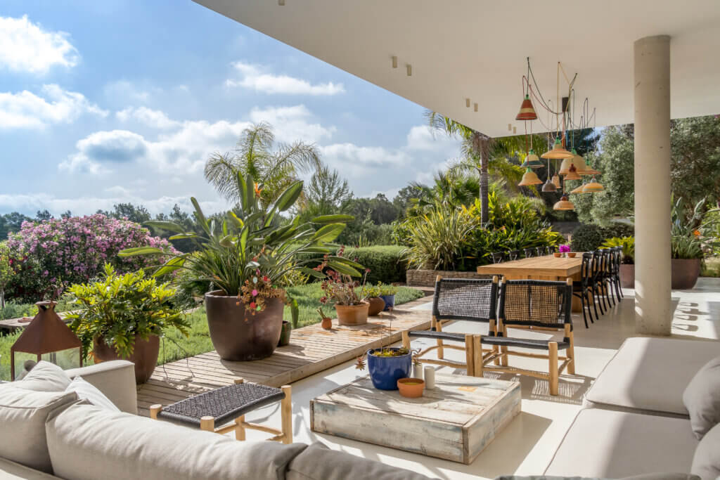 Modern outdoor lounge and dining area of luxury villa Can Paloma featuring lush tropical gardens and designer lighting.