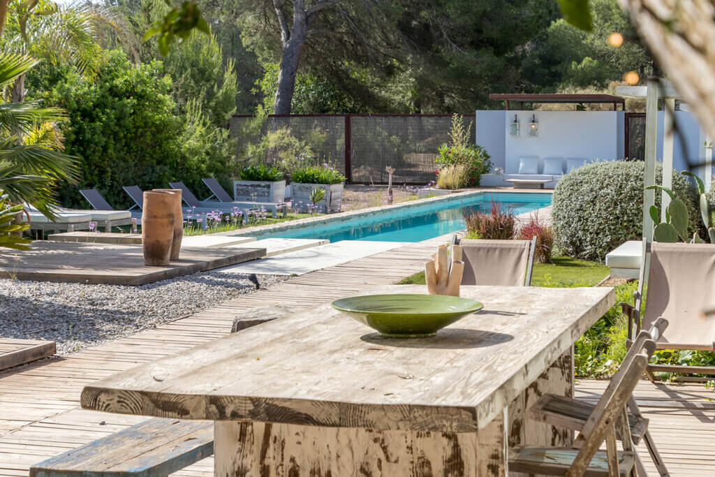 Sun-drenched outdoor dining table overlooking a luxury villa lap pool at Can Paloma.
