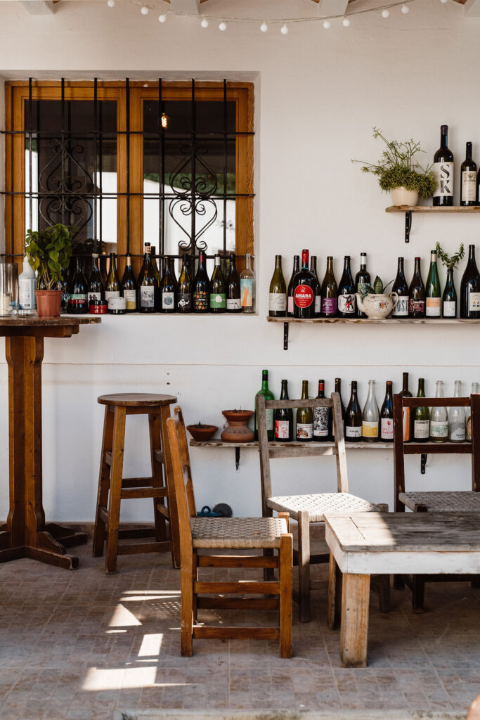 Wine bottles displayed on shelves in the rustic dining room at Casa Lhasa, Ibiza.