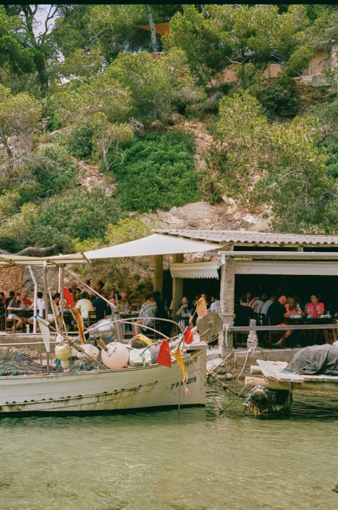 Boat moored beside a busy waterfront restaurant in Ibiza.