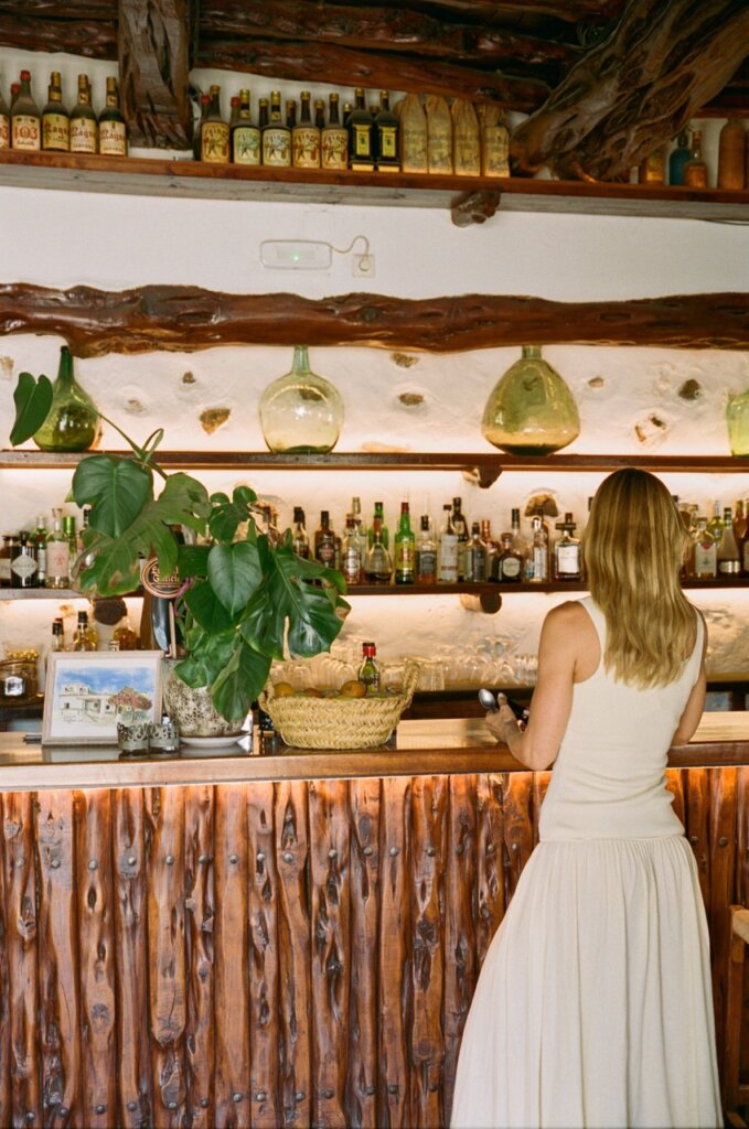 Woman at the counter of a rustic Ibiza bar, an outing during a stay at Can Paloma villa.