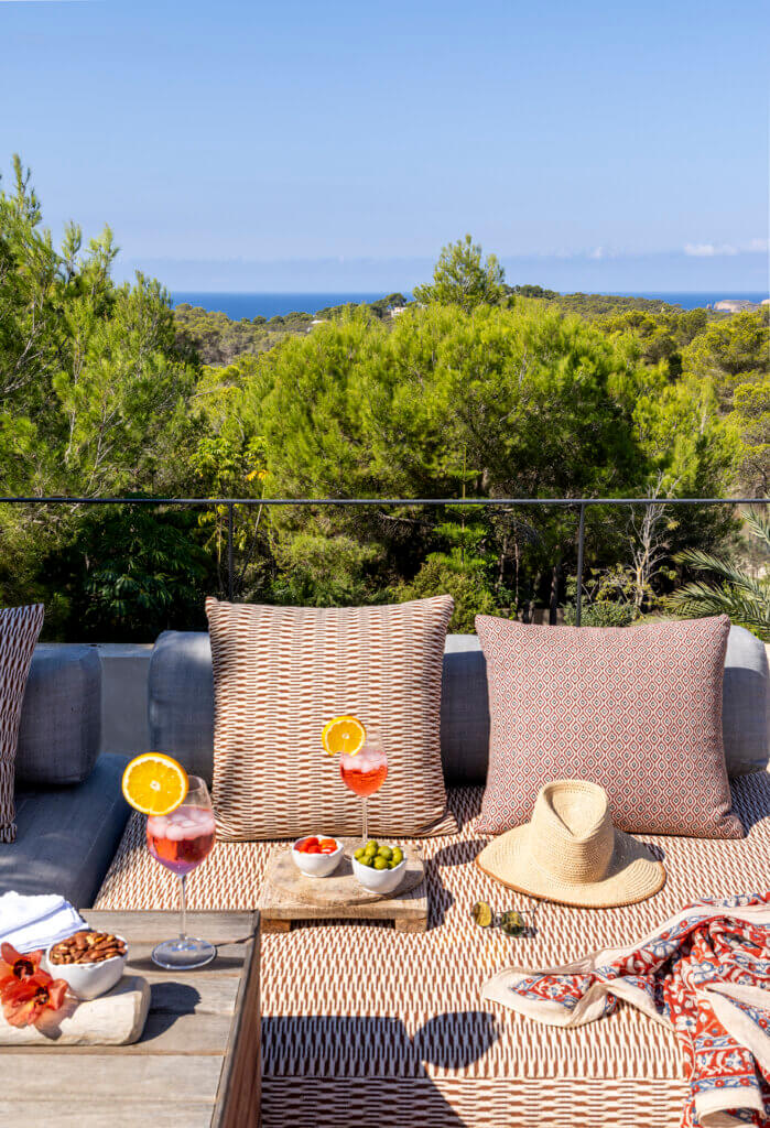 A sun-drenched rooftop terrace at luxury Villa Anaïs with patterned cushions, cocktails, and olives overlooking the sea.