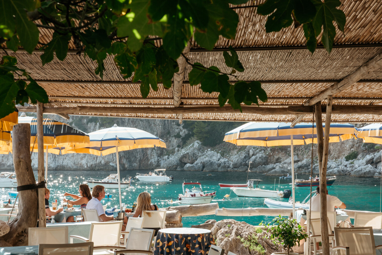 Outdoor dining at a Capri beach club overlooking the Mediterranean Sea and rocky coastline