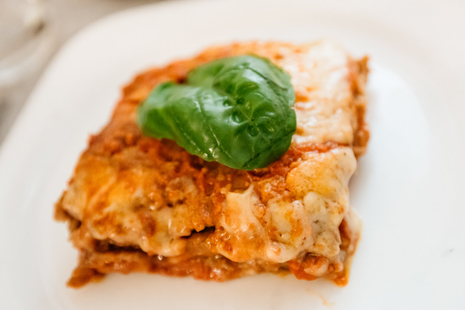 Slice of baked lasagna topped with fresh basil