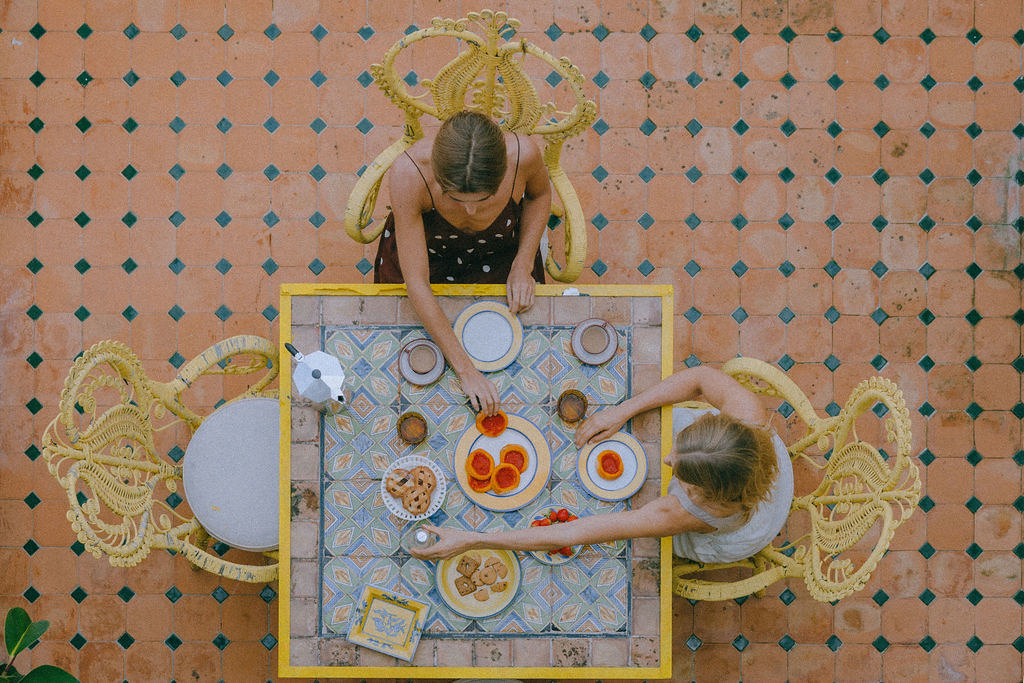 Outdoor breakfast table set with pastries and fruit on a colorful tiled terrace
