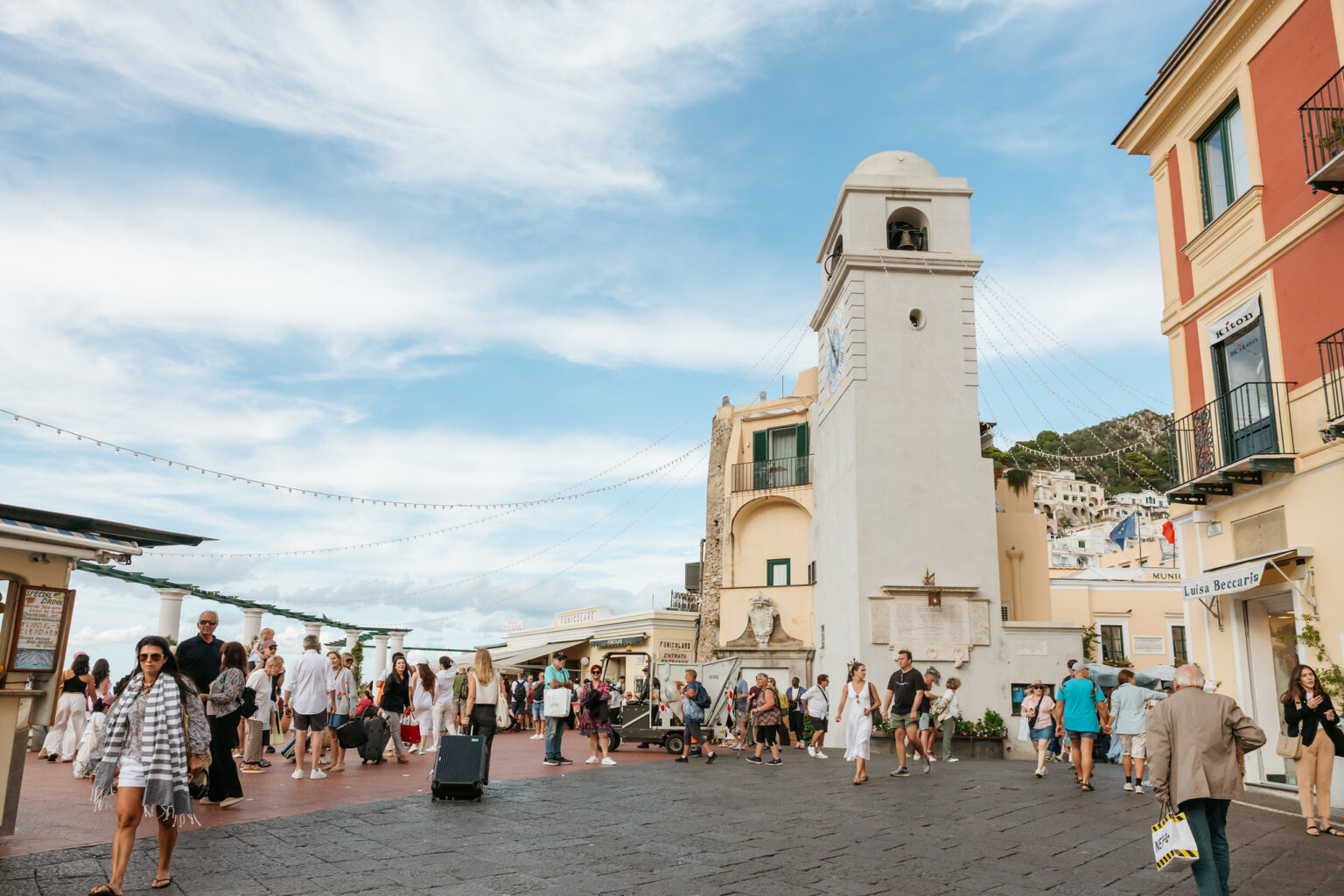 Visitors gathering in Capri's lively town square beside the historic bell tower