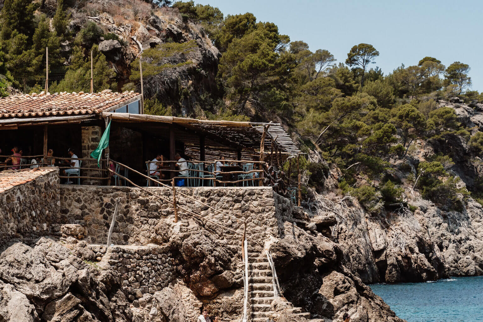 Turquoise Mediterranean cove surrounded by rocky cliffs and pine trees in Mallorca