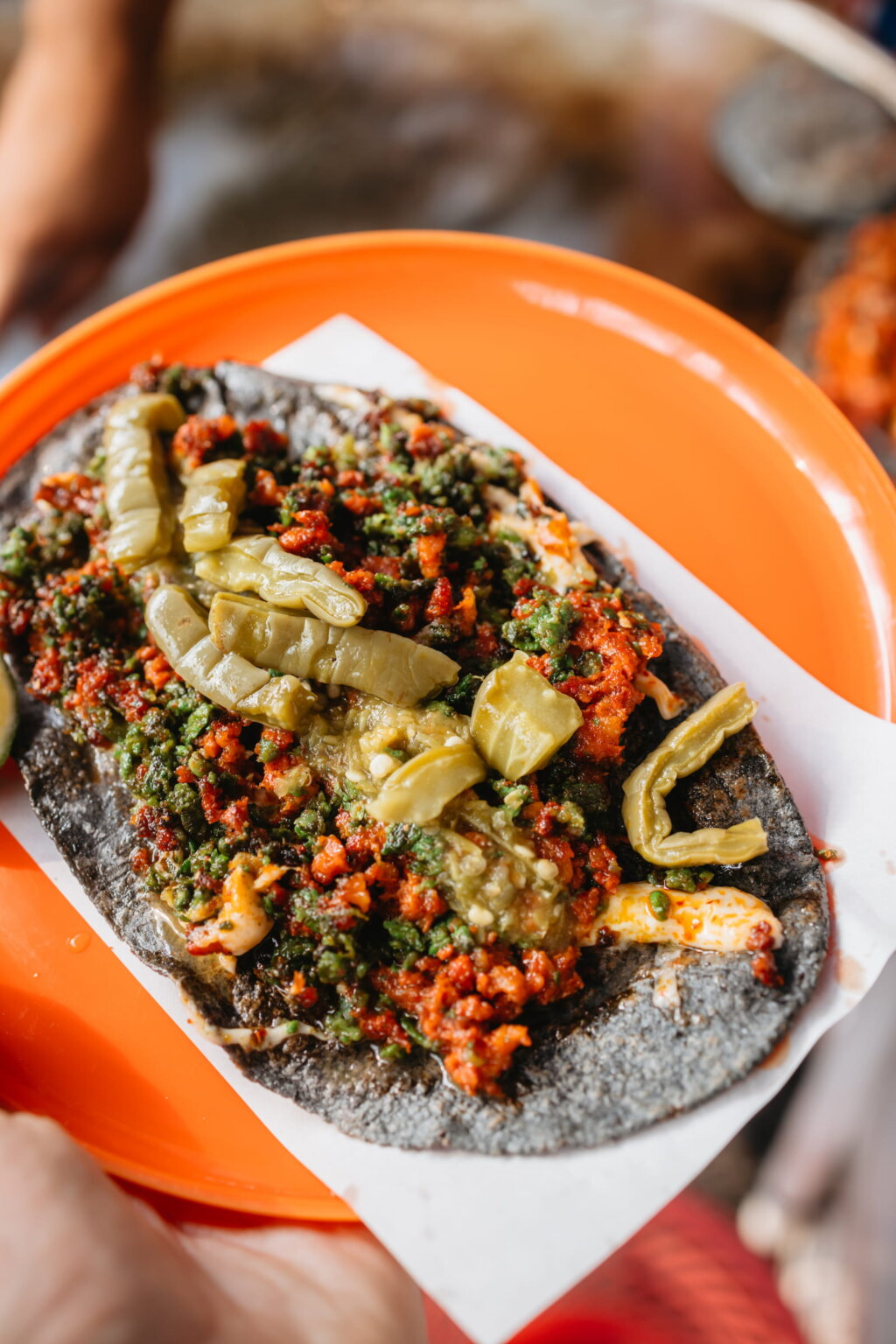 Black corn tostada topped with salsa, vegetables and pickled peppers in Mexico City