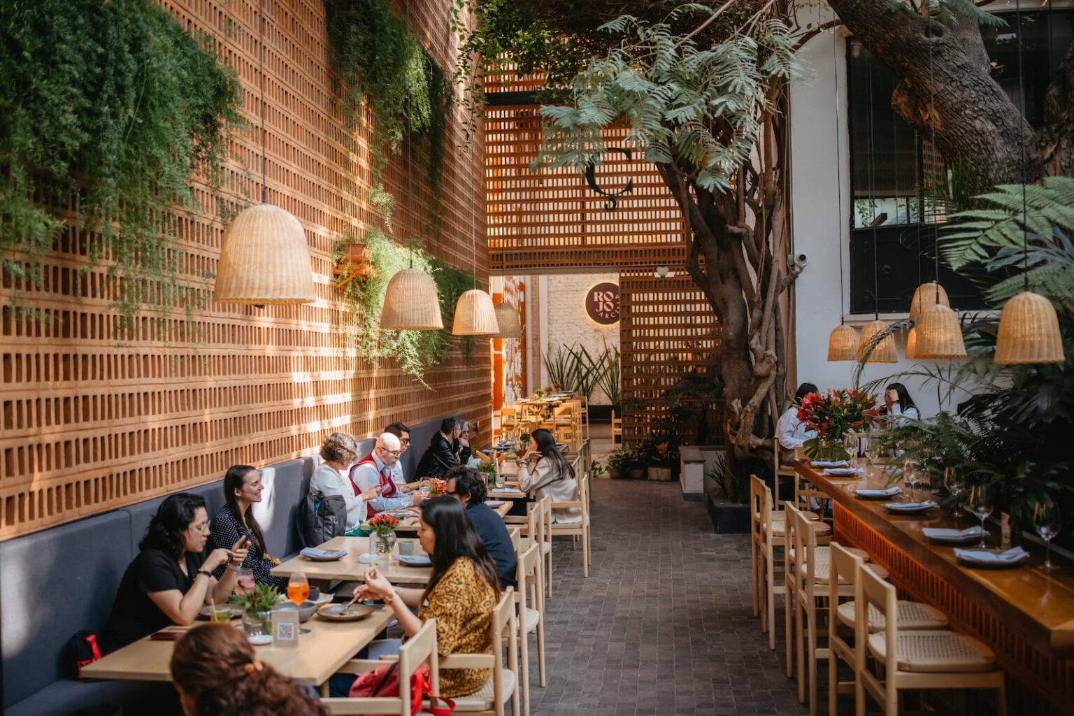 Guests dining in a lush Mexico City restaurant with natural wood and greenery