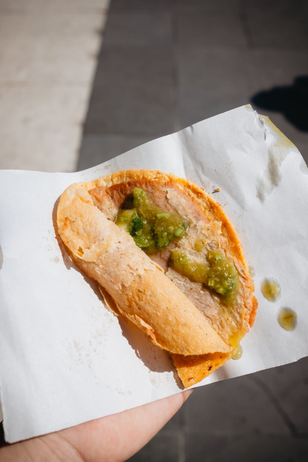 Close-up of a Mexican taco with green salsa served as street food