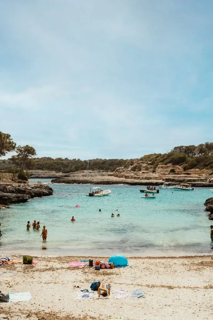 Cala Mondragó with turquoise Mediterranean water surrounded by rocky cliffs and pine trees in Mallorca,